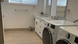 Une buanderie moderne équipée d’un lave-linge, d’un sèche-linge et d’un évier.