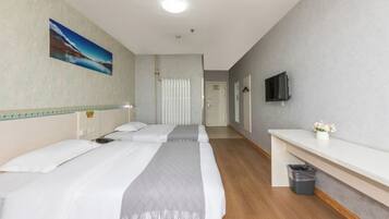A hotel room with two beds, a TV, a small desk, and a trash bin.
