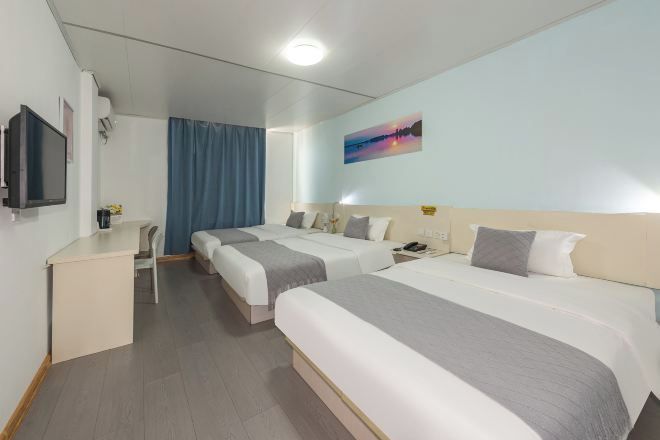 A hotel room with two beds, a desk, a chair, a TV, and a painting on the wall.