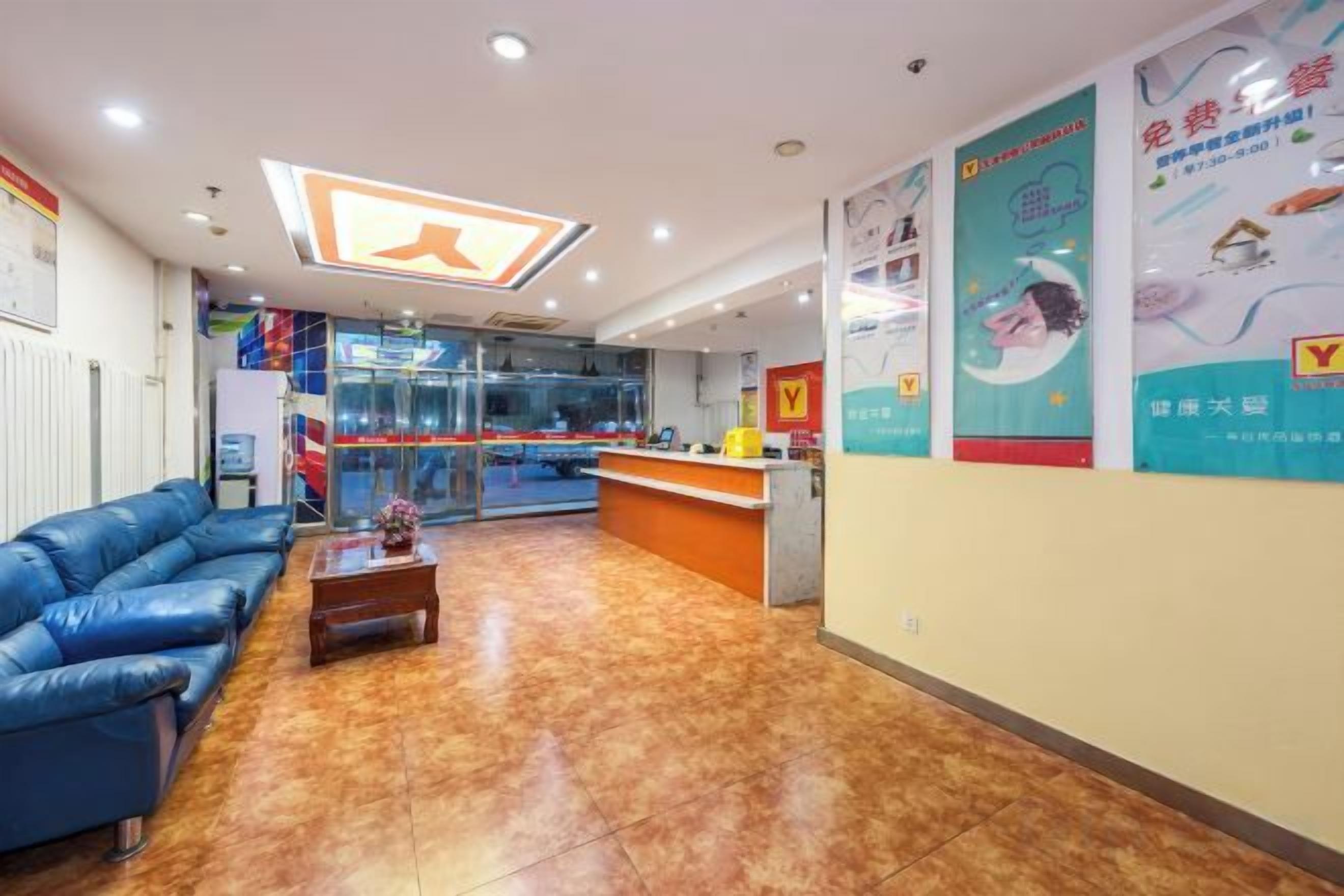 A reception area with a reception desk, blue seating, and a tiled floor.