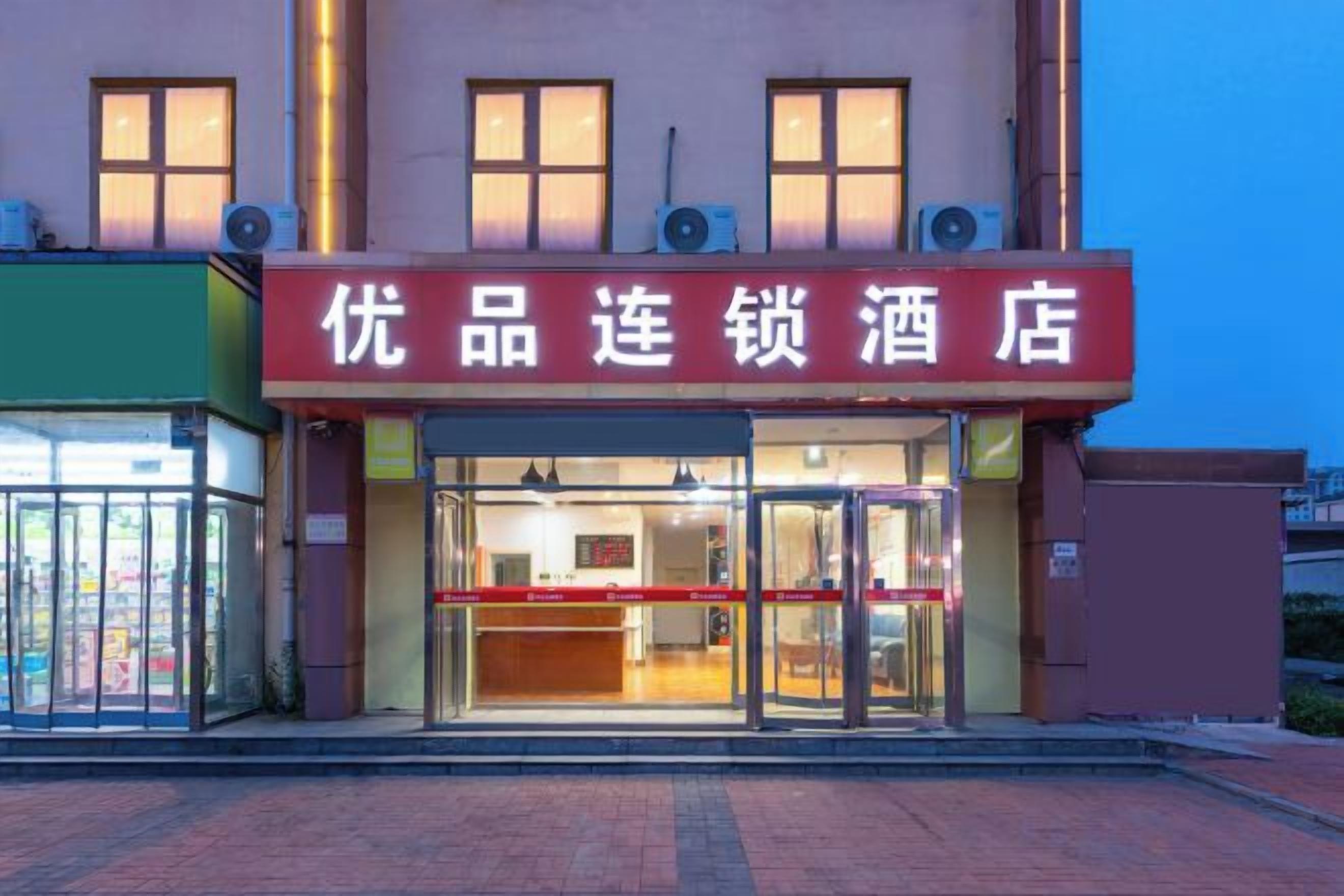 A hotel entrance with a glass door and a red sign above.