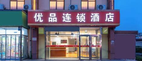 A hotel entrance with a glass door and a red sign above.