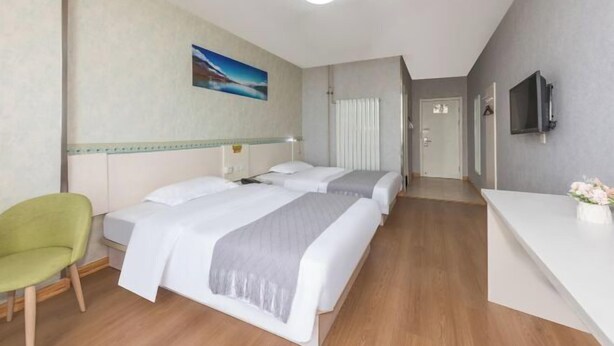 A hotel room with two beds, a desk, a TV, and a painting on the wall.