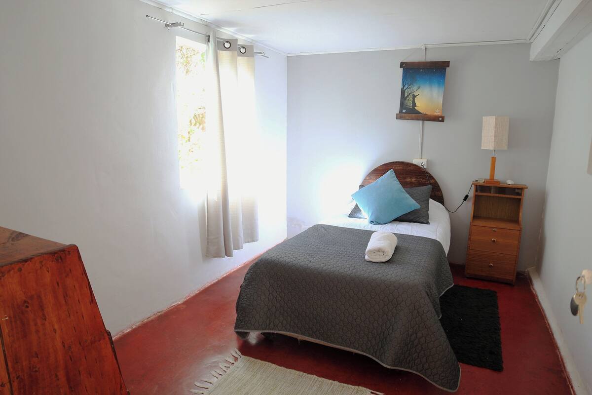 Une chambre à coucher avec un lit, une table de chevet, une lampe et un tableau au mur.