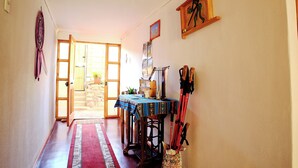 A hallway with a wooden table, a red and blue rug, and a door leading to a bright room. - Casa Pumagui (Vicuña)