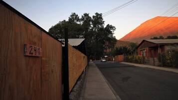 Vista de la calle con una cerca de madera, un letrero con 'ZIM' y un edificio con techo rojo al fondo.