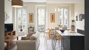 A modern apartment with a living room, dining area, and kitchen. There are large windows, a TV, and a dining table with chairs. - Sunlight Properties GISELE: Hyper centre, 1 bedroom with bright modern living (Nice)