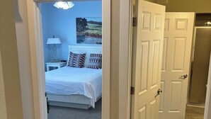 A bedroom with a bed, a nightstand, a lamp, and a painting on the wall.