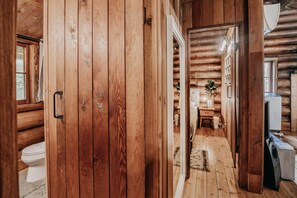 A wooden cabin interior with a visible toilet, a small table with a plant, and a washing machine. - 76gs - Genuine Log Cabin - Wifi - Pets Ok - Sleeps 4 (Deming)