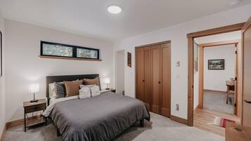 Un dormitorio con una cama grande, un armario de madera y una ventana con vistas a árboles.