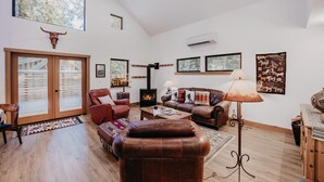 Un salon spacieux avec des canapés en cuir, une cheminée et de grandes fenêtres.