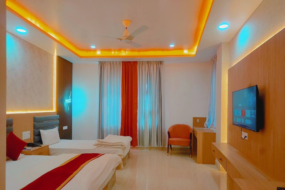 Quarto de hotel com duas camas, televisão, escrivaninha e uma cadeira.
