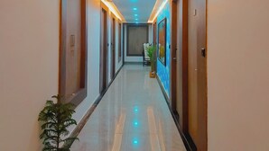 Pasillo de hotel con piso pulido, puertas a ambos lados e iluminación empotrada.
