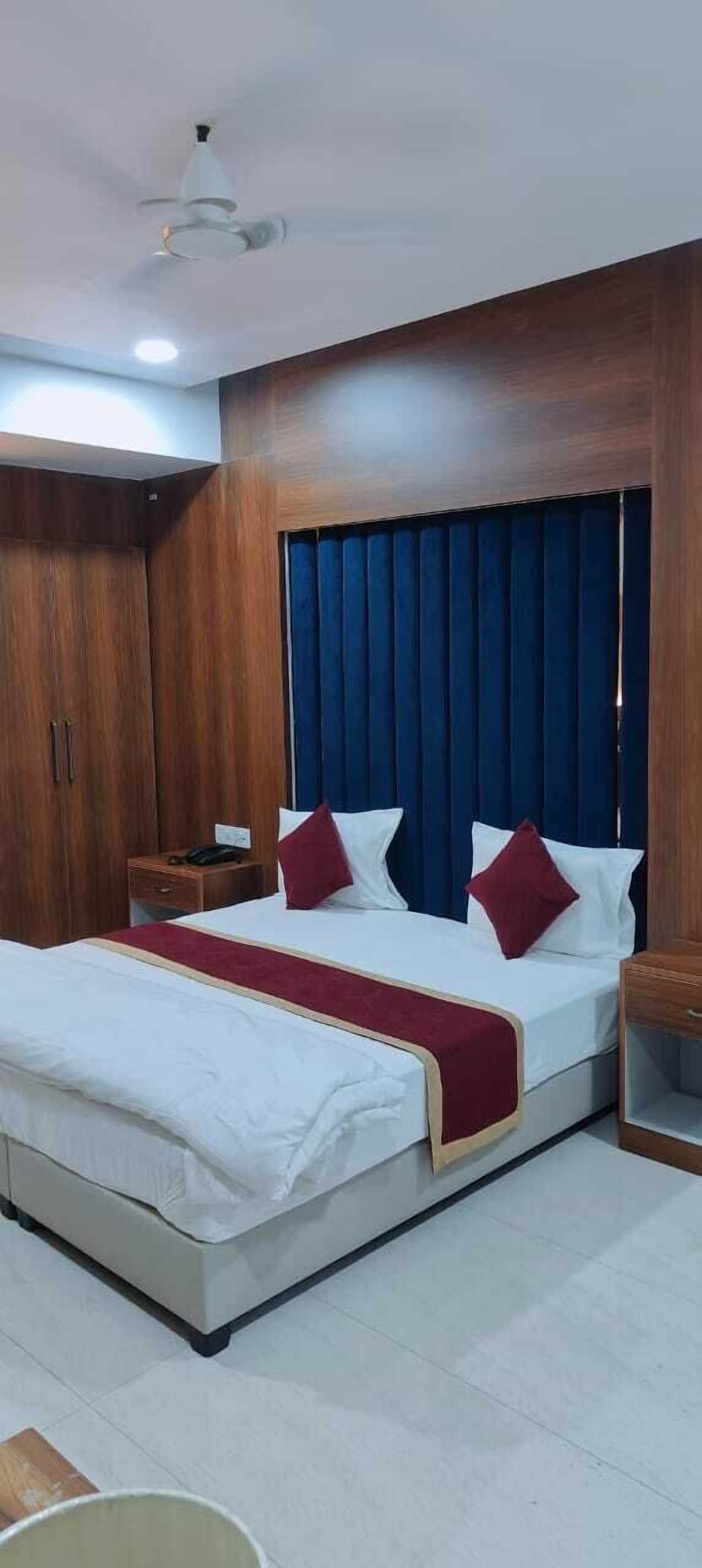 Ein Hotelzimmer mit einem großen Bett, einem Holzschrank, einem Nachttisch und einem Deckenventilator.