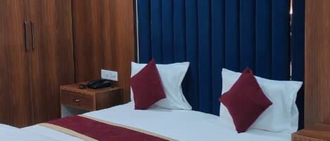 Ein Hotelzimmer mit einem großen Bett, einem Holzschrank, einem Nachttisch und einem Deckenventilator.