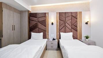 Un dormitorio moderno con dos camas, cabeceros de madera, mesitas de noche e iluminación empotrada en la pared.