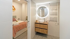 Ein modernes Badezimmer mit einem runden Spiegel, einem weißen Waschbecken und einem Handtuchhalter.