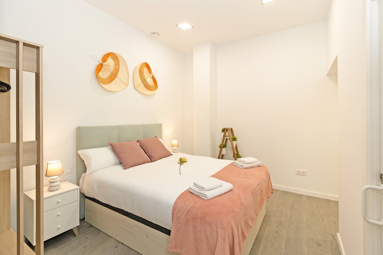 A modern bedroom with a bed, bedside tables, a mirror, and decorative wall art.