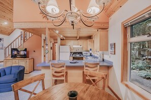 A modern kitchen with wooden cabinets, a central island, and a dining area with a table and chairs.
