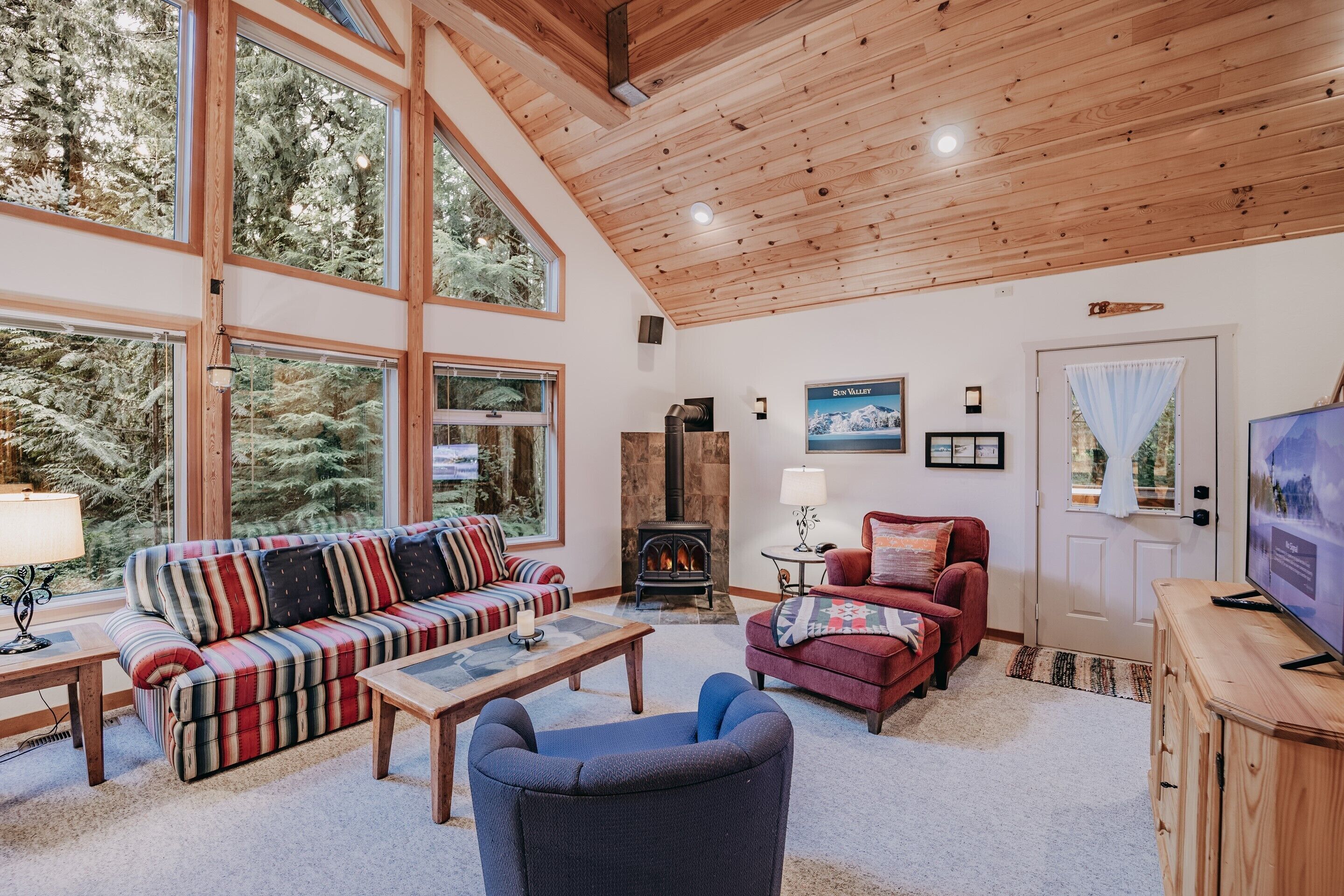A cozy living room with a large window, a fireplace, and a television.