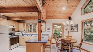 Una cocina con armarios de madera, una isla central y un comedor con sillas.