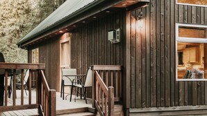 Una cabaña de madera con porche, mobiliario exterior y una cocina a la vista.