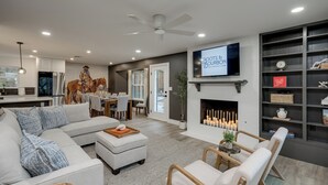 A modern living room with a sectional sofa, a fireplace, and a mounted TV. -  5-Bedroom Retreat with Cowboy Pool, Sauna and More – 10 Min to Downtown Austin (Austin)