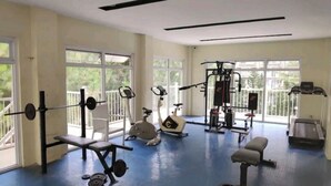 Un gimnasio con equipamiento de ejercicio, ventanas amplias y suelo azul.