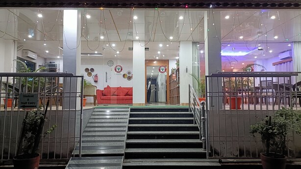 A hotel entrance with a staircase, a red sofa, and a sign indicating student and staff entry. - The Bodhgaya Hotel School (Bodh Gaya)