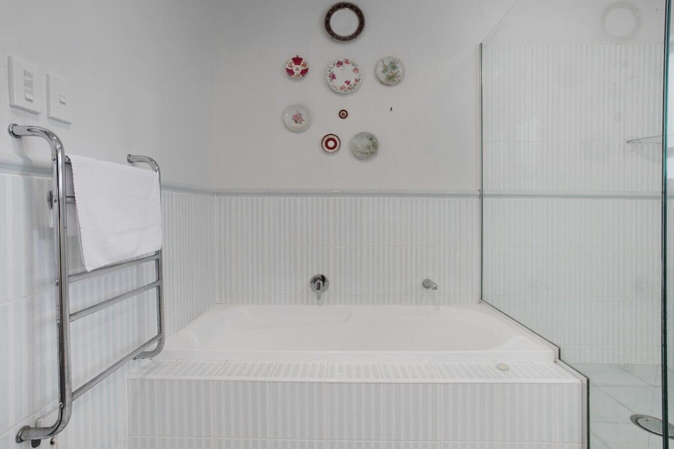 A modern bathroom with a large bathtub, a glass shower enclosure, and a towel rack with a white towel.