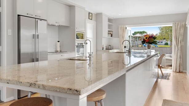 Una cocina moderna con una isla grande, electrodomésticos de acero inoxidable y vistas al exterior.