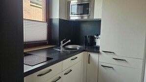 Una cocina moderna con microondas integrado, un lavamanos y una cafetera.