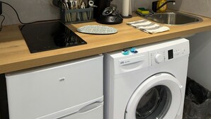 A compact kitchen with a microwave, coffee maker, and a washing machine.