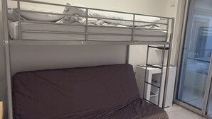 A bunk bed with a mattress on the lower bunk and a sofa on the upper bunk.