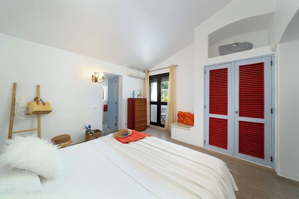 A bedroom with a bed, a wardrobe, a window, and a door.
