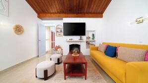 A living room with a wooden ceiling, a yellow sofa, a TV, and a fireplace. - 🔥Is Oura Calling You?🔥4BD Sleeps 12 Jacuzzi Pool PingPong 5min Strip 10' beach (Albufeira)