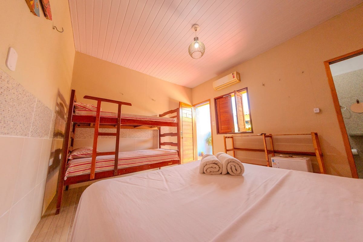 A room with bunk beds, a bedside table, a mirror, and an air conditioning unit.