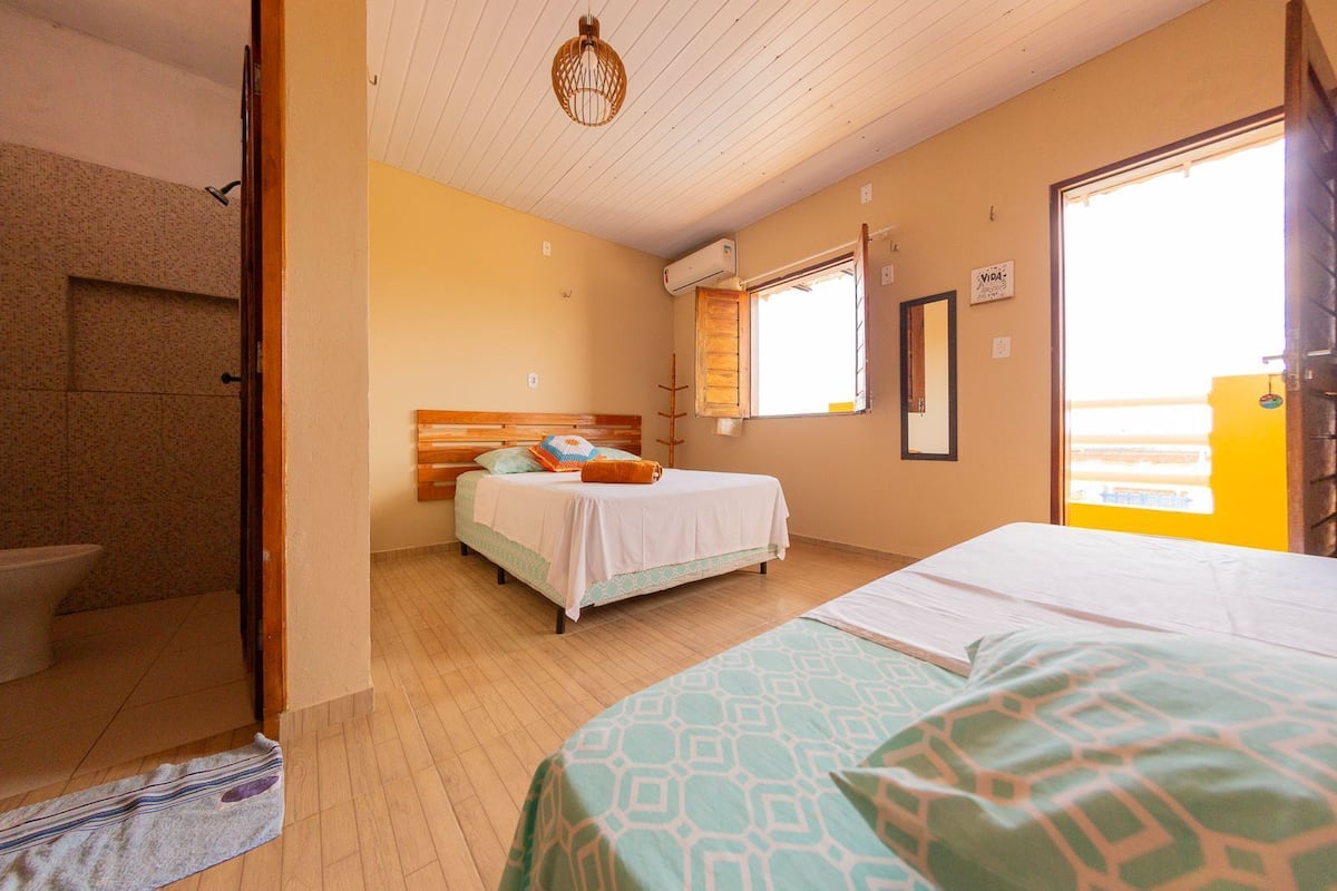 A bedroom with a bed, a window, and a shower area.