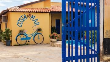 Um edifício com fachada amarela, um desenho de bicicleta azul e um portão azul.