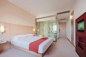 Una habitación de hotel con cama, televisión, cabina de ducha de vidrio y armario de madera.