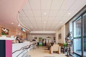 Un vestíbulo de hotel con mostrador de recepción, zona de estar y una estatua.