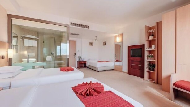 A hotel room with two beds, a large mirror, a TV, and a small seating area. - Longma Ginza Hotel (Yuxi)