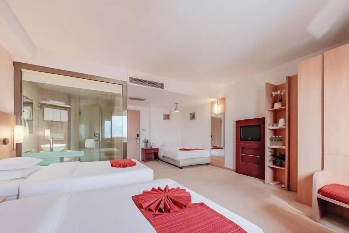 Une chambre d’hôtel avec deux lits, un grand miroir, une télévision et un petit coin salon.