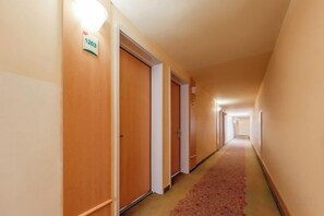 Un pasillo de hotel con puertas de madera, placas de números de habitación y suelo alfombrado.