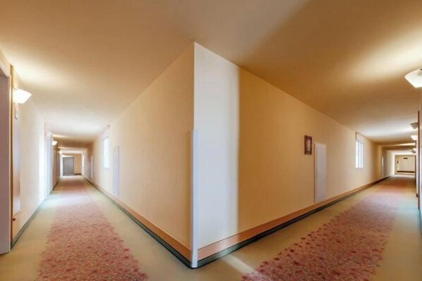 A long, narrow hotel corridor with a carpeted floor and a light-colored wall. - Longma Ginza Hotel (Yuxi)