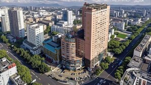 A high-rise building with a rooftop terrace, surrounded by other buildings and a clear sky. - Longma Ginza Hotel (Yuxi)