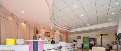 A reception area with a curved counter, seating, and a ceiling with recessed lighting.