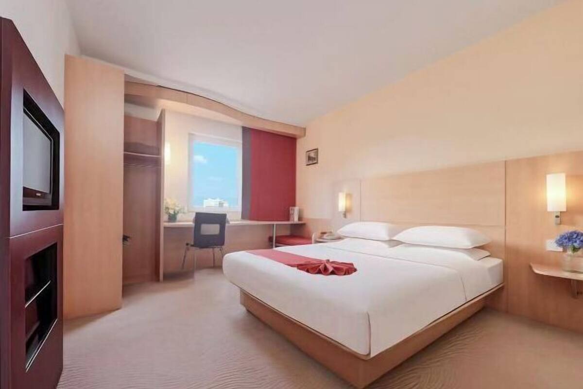 Une chambre d’hôtel équipée d’un lit, d’un bureau, d’une chaise et d’un téléviseur.