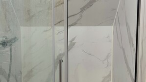 A glass-enclosed shower with a marble finish. - Cosy and Comfy Double Room with Private Bathroom, Close to o2 Arena (London)