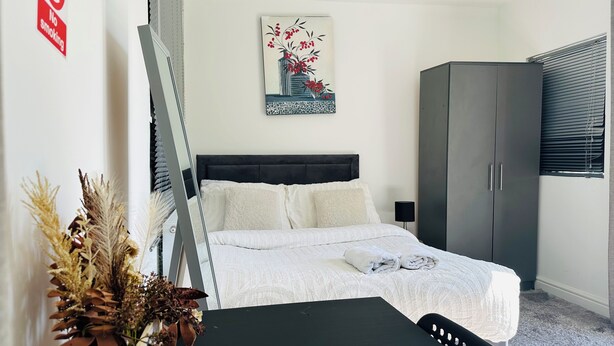 A bedroom with a bed, a wardrobe, a painting, and a plant. - Cosy and Comfy Double Room with Private Bathroom, Close to o2 Arena (London)